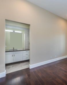 Modern living room in Whittier with dark hardwood floors, corner windows with shutters, and a stylish chandelier for a contemporary touch.