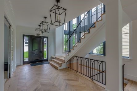 Modern stairway with custom wood treads, sleek black iron railings, and floor-to-ceiling windows in a remodeled South Whittier home.