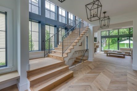 Modern stairway with custom wood treads, sleek black iron railings, and floor-to-ceiling windows in a remodeled South Whittier home.