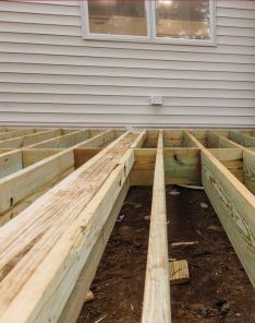Side view of new deck installation with upright support posts, ready for finishing, in a Santa Fe Springs backyard.