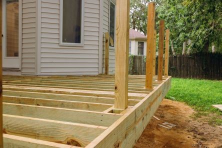 Side view of new deck installation with upright support posts, ready for finishing, in a Santa Fe Springs backyard.